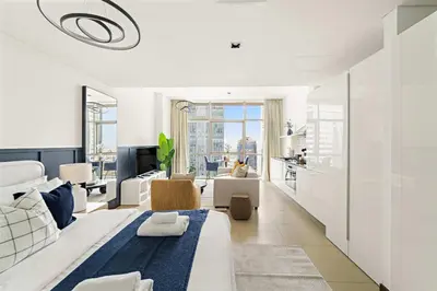 a white bedroom with a large bed and a living room at Silkhaus Comfy Studio in Liberty House DIFC Heart in Dubai