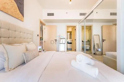 a bedroom with a large white bed with two towels at Community View 1BR with Balcony Near Downtown Dubai, Binghatti Avenue, Al Jaddaf by Deluxe Holiday Homes in Dubai