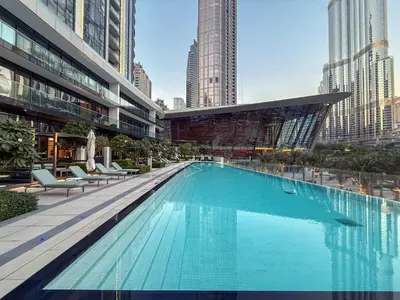 a large swimming pool in a city with tall buildings at Hermes-Style 2BR, Full Burj Khalifa View - Infinity Pool - Full Fountain View in Dubai