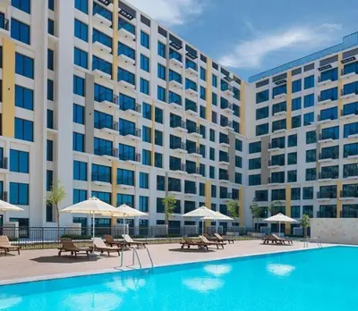 a large building with a pool and chairs and umbrellas at Pure Voyage Town Square in Dubai