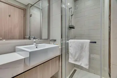 a white bathroom with a sink and a shower at GuestReady - Riviera Studio | Burj Khalifa view in Dubai