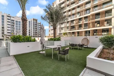 an apartment patio with tables and chairs and palm trees at GuestReady - Riviera Studio | Burj Khalifa view in Dubai