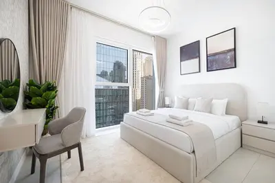 a white bedroom with a bed and a desk and a window at La Vie in JBR! Private Beach! Excellent Apartments! in Dubai