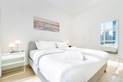 a white bedroom with a large bed and a window at Stylish 1-Bedroom with Stunning Marina Views at Dorra Bay in Dubai