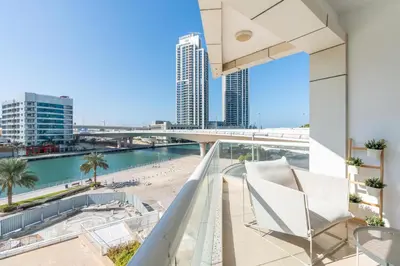 a balcony with a chair and a beach and buildings at Stylish 1-Bedroom with Stunning Marina Views at Dorra Bay in Dubai