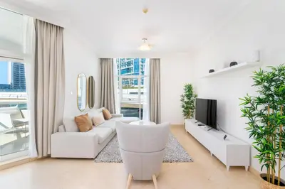 a white living room with a couch and a tv at Stylish 1-Bedroom with Stunning Marina Views at Dorra Bay in Dubai