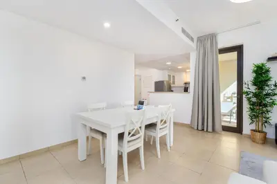 a white dining room with a white table and chairs at Spacious 1-Bedroom at the Heart of JBR in Dubai
