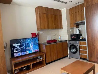 a small kitchen with a tv and a washer at Cozy Studio in Dubai