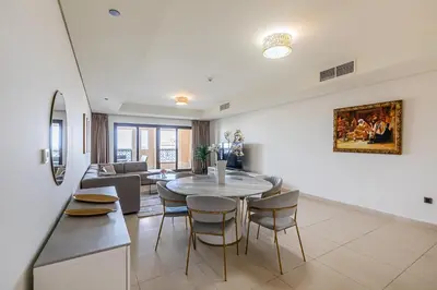 a dining room and living room with a table and chairs at Balqis I Renovated 3BDR with 1 maid room I Palm Jumeirah in Dubai