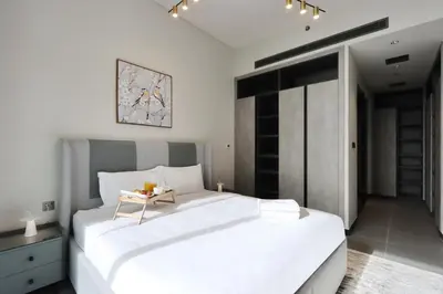 a white bedroom with two beds and a table at Livbnb-Embrace Luxury and Comfort in Prime 1BR,JLT in Dubai