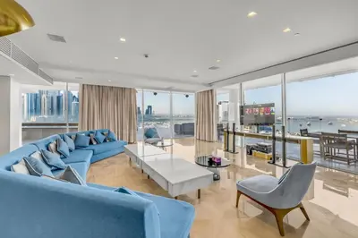 a living room with blue furniture and large windows at luxury penthouses see view at five in Dubai