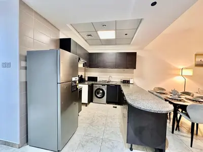 a kitchen with a refrigerator and a table with chairs at Cozy Family-Friendly 2BR in JVT in Dubai