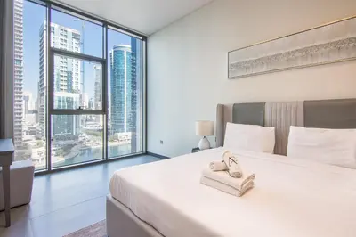 a bedroom with a large white bed and large windows at MBL Royal, JLT -One Bedroom with Lake View in Dubai