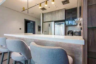 a kitchen with a bar with chairs around it at MBL Royal, JLT -One Bedroom with Lake View in Dubai
