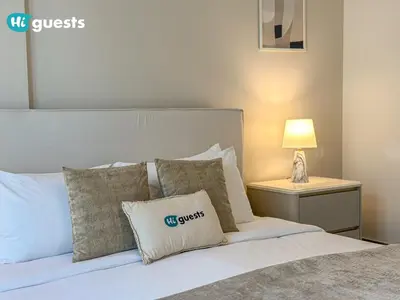 a bedroom with a bed with pillows and a lamp at HiGuest - Coastal Luxury 2BR in La Mer Beachside Bliss in Dubai
