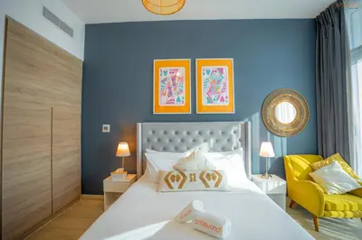 a bedroom with a white bed and a yellow chair at Bnbeyond's Sheek Studio at Studio One tower in Dubai