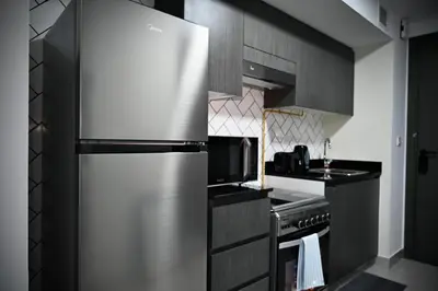 a kitchen with a stainless steel refrigerator and a stove at Fully Furnished Elegant Studio Apartment Close by Dubai Science Park, Dubai Miracle Garden, Butterfly Garden and Dubai Hills Mall in Dubai