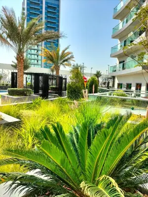 a park with palm trees and a building at Fully Furnished Elegant Studio Apartment Close by Dubai Science Park, Dubai Miracle Garden, Butterfly Garden and Dubai Hills Mall in Dubai