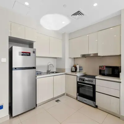 a kitchen with white cabinets and a stainless steel refrigerator at Park Point C-1 bedroom for monthly stay-1004 in Dubai