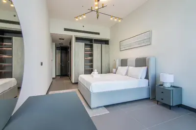 a white bedroom with a bed and a lamp at MBL Royal, JLT- 1-BR Apartment with Lake View in Dubai
