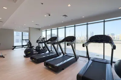 a gym with several treadmills in a room with windows at GuestReady - Contemporary retreat at Azizi Gardens in Dubai