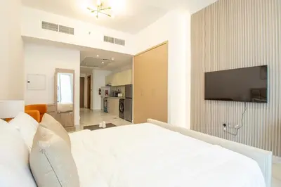 a bedroom with a white bed and a flat screen tv at Millenium Binghatti Residences Business Bay- Stylish Studio with Canal View in Dubai