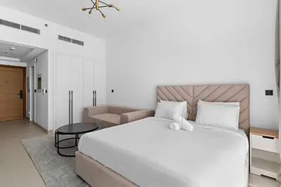 a bedroom with a large white bed and a chair at Modern Studio in Al Furjan with pool and gym in Dubai