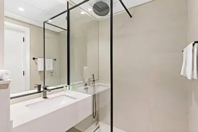 a white bathroom with a sink and a shower at Modern Studio in Al Furjan with pool and gym in Dubai