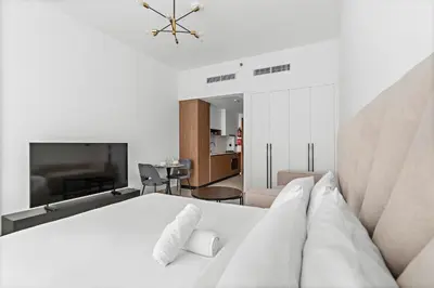 a bedroom with a white bed and a living room at Modern Studio in Al Furjan with pool and gym in Dubai