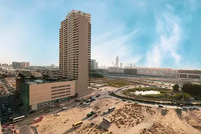 a tall building in a city with a parking lot at Modern 1-Bedroom Apartment with Luxurious Amenities in JVC in Dubai
