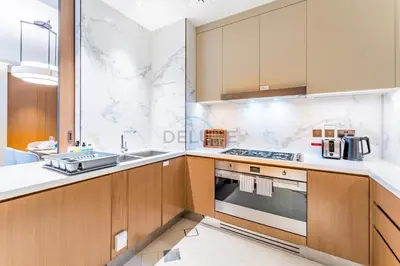 a kitchen with wooden cabinets and a sink and a stove at Overlooking Burj Khalifa and Fountain Views from Living to Bedrooms, The Address Residences Dubai Opera Tower 2, Downtown Dubai by Deluxe Holiday Homes in Dubai