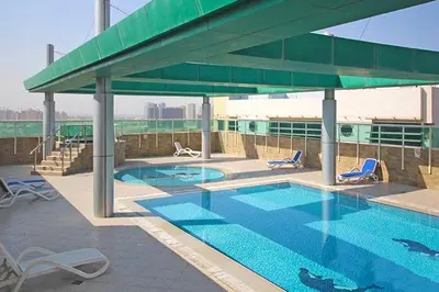 a swimming pool with chairs and a large umbrella at Modern Studio Retreat in Sports City Dubai in Dubai