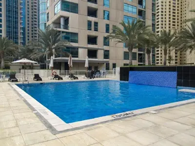a large swimming pool with palm trees and buildings at HAVN - 1 Bed in Dubai Marina, 5mins walk to JBR in Dubai