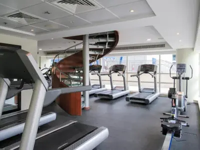 a gym with several treadmills and a spiral staircase at HAVN - 1 Bed in Dubai Marina, 5mins walk to JBR in Dubai