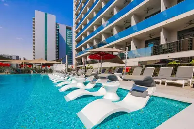 a swimming pool with white lounge chairs and a building at Cozy Studio Steps from Dubai Mall & Burj Khalifa in Dubai