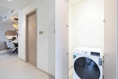 a washing machine in a hallway with a dining room at Sky High Luxury, Grande Signature, Burj Khalifa View, 5 minute walk to Dubai Mall in Dubai