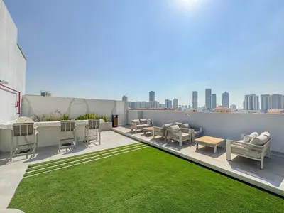 a rooftop patio with chairs and a green lawn at Luxury 1BR Haven Chic & Cozy Stay in JVC in Dubai