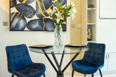 a glass table with two blue chairs and a vase with flowers at Studio in downtown with Burj Khalifa and city view in Dubai