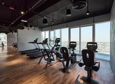 a gym with treadmills and exercise bikes in a room with windows at Airvistas retreat at wasl one residence in Dubai
