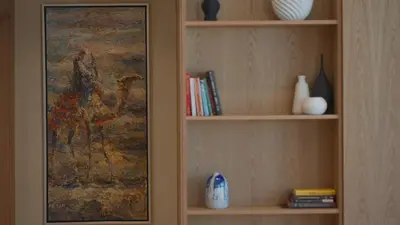 a book shelf with books and vases and a painting at Mori - luxury Burj full view in Dubai