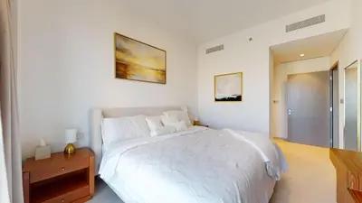 a white bedroom with a bed and a wooden table at Best 2 bedroom Direct Burj Khalifa Downtown View in Dubai