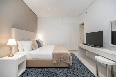 a white bedroom with a bed and a tv at Cozy and elegant Studio in Business Bay in Dubai