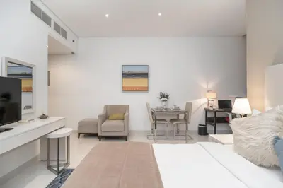a white living room with a bed and a desk at Cozy and elegant Studio in Business Bay in Dubai