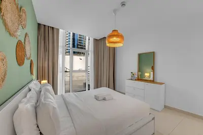 a white bedroom with a bed and a mirror at Waves - Charming Apt With Balcony Steps From The Beach in Dubai