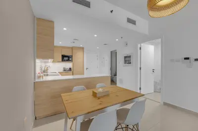 a kitchen and dining room with a wooden table and chairs at Waves - Charming Apt With Balcony Steps From The Beach in Dubai