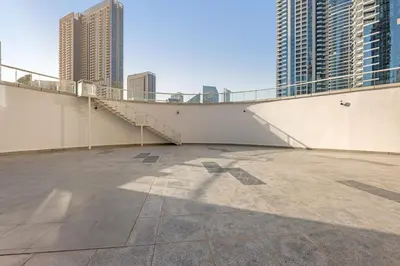 a walkway on a roof with buildings in the background at Waves - Charming Apt With Balcony Steps From The Beach in Dubai
