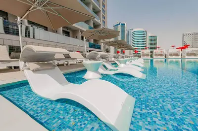 a swimming pool with white lounge chairs and an umbrella at Luxury Studio Near Dubai Mall few mints walk in Dubai