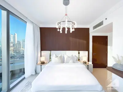 a bedroom with a large white bed and a chandelier at Elegant 2B at Boulevard Point Burj & Fountain View in Dubai