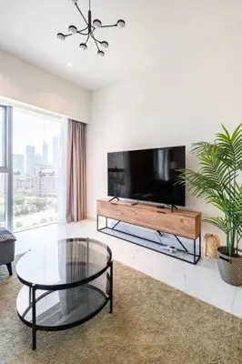 a living room with a tv and a glass table at Central Park Tower DIFC - 10 Minutes Walk to Metro - Spacious 1BDR in Dubai