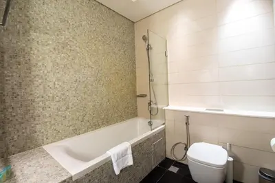 a bathroom with a tub and a toilet and a sink at Central Park Tower DIFC - 10 Minutes Walk to Metro - Spacious 1BDR in Dubai